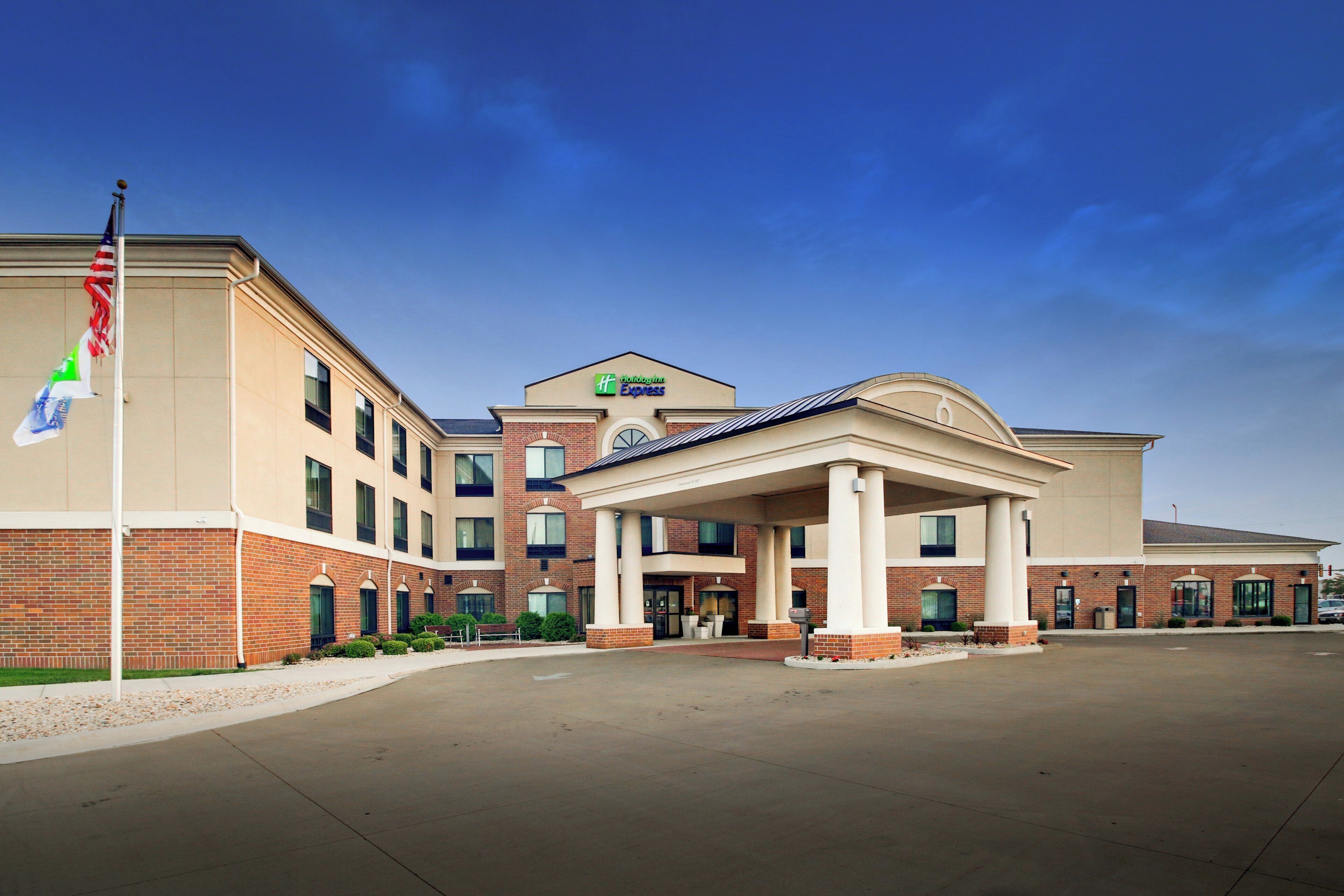 Een Holiday Inn Express hotel met een bakstenen gevel, een overdekte ingang en een wimpelstok met meerdere vlaggen.