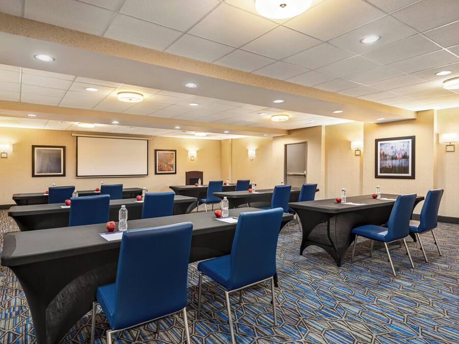 A conference room with tables, chairs, and presentation screens.