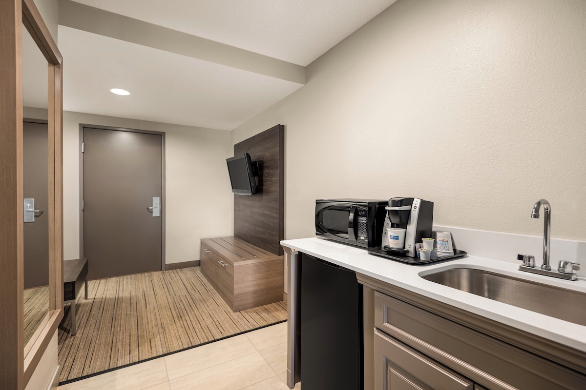 A compact hotel room with a kitchenette, a microwave, a coffee maker, and a sink.