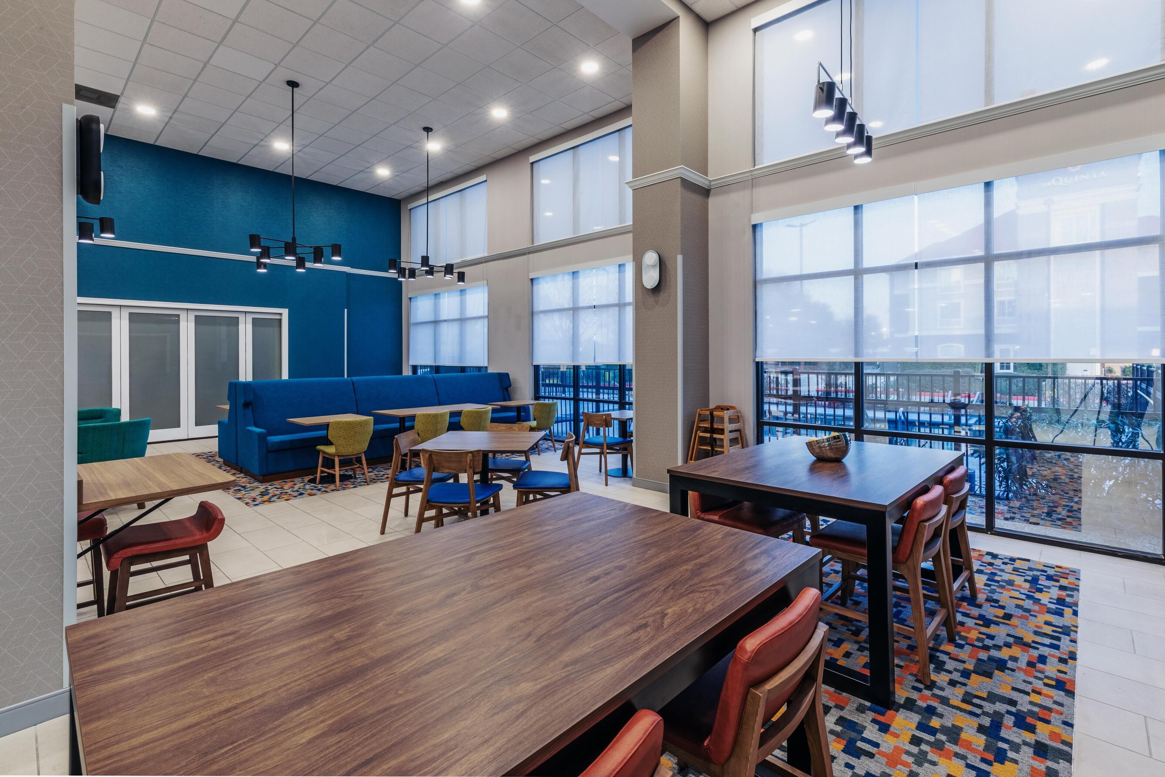 A modern interior with a blue accent wall, large windows, and a mix of seating arrangements including tables and chairs.
