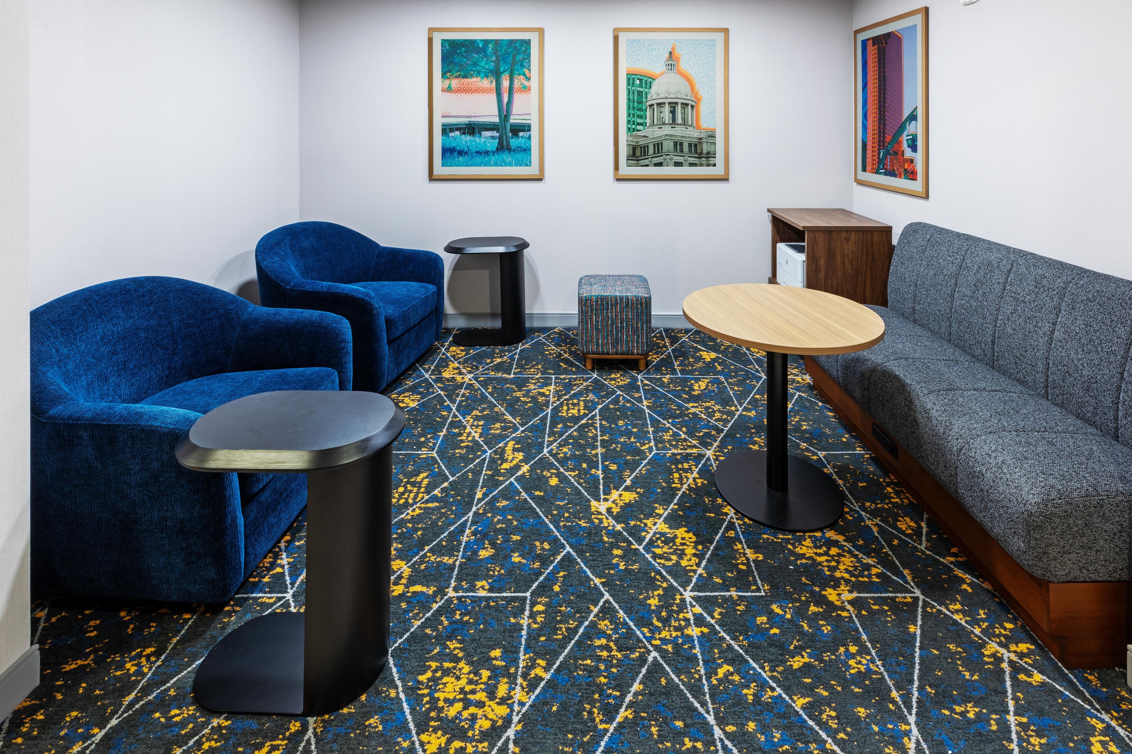 A room with a blue sofa, two blue armchairs, a small round table, and a patterned carpet.