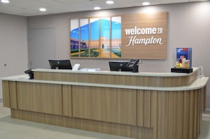 Una mesa de recepción con un cartel que dice "Welcome to Hampton", una computadora y un teléfono.