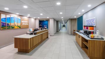 A hotel reception area with a long corridor, reception desks, and a 'Welcome to Hampton' sign.