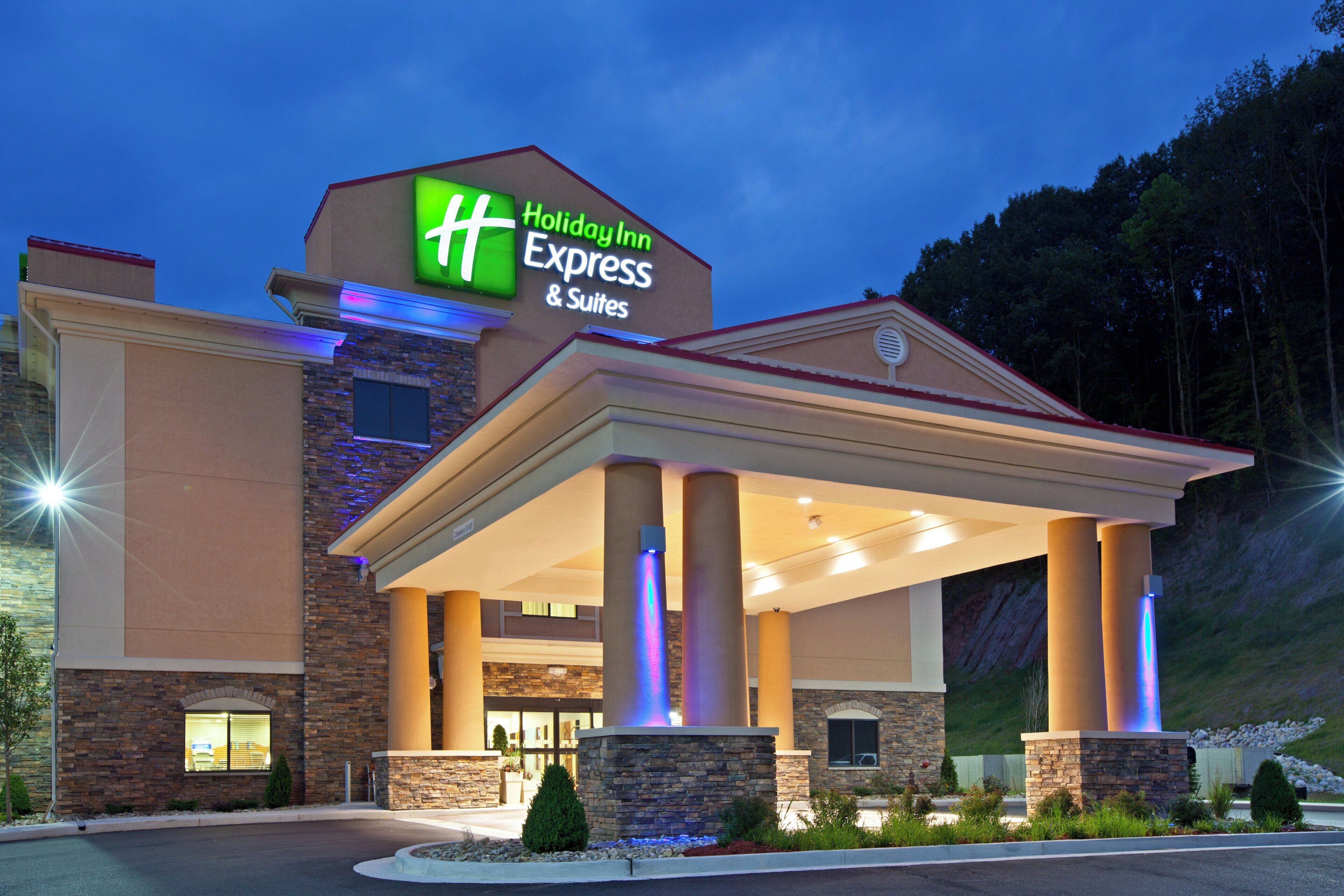 Edifício da Holiday Inn Express & Suites, com entrada coberta e fachada de pedra.