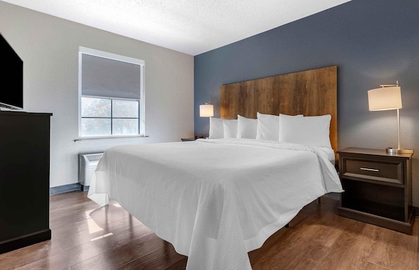 Habitación de hotel con una cama grande, una mesita de noche, una lámpara, una ventana y un televisor.