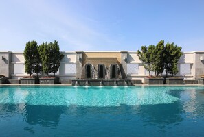 Une piscine agrémentée d’une cascade et bordée d’arbres.