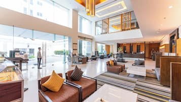 A spacious lobby with a reception desk, seating area, and a glass entrance.
