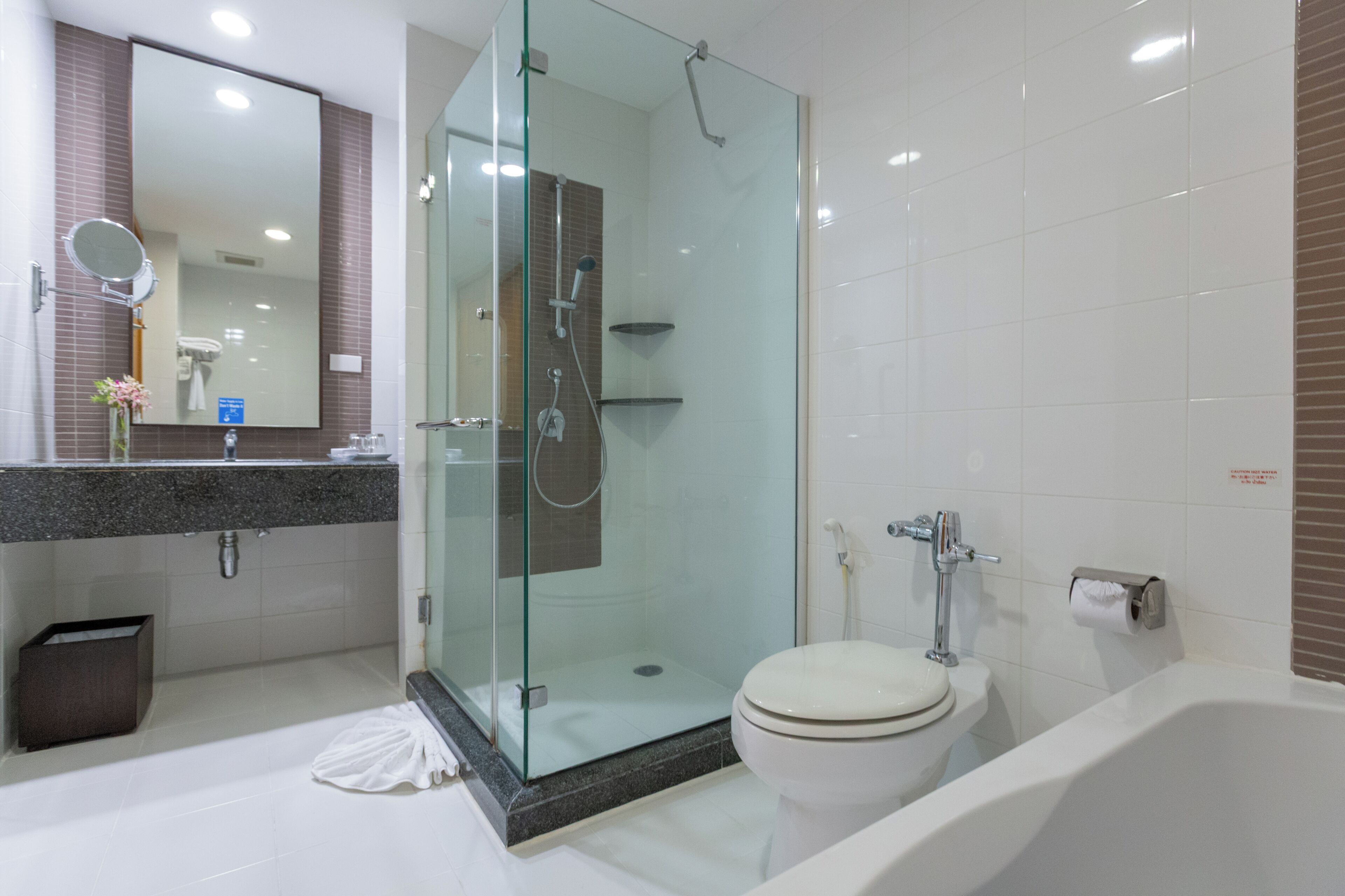 A modern bathroom with a glass-enclosed shower, a white toilet, and a marble countertop.