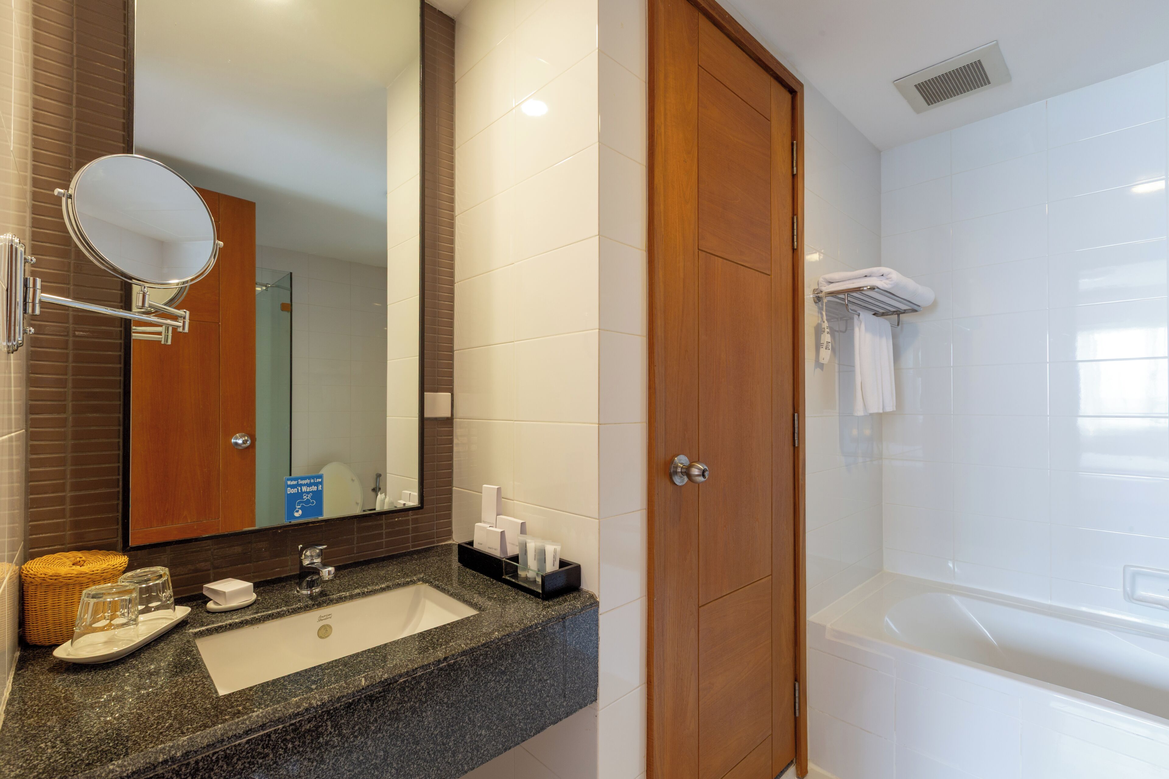 A bathroom with a sink, mirror, and a wooden door leading to a shower area.