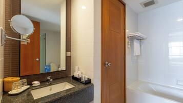 A bathroom with a sink, mirror, and a wooden door leading to a shower area.