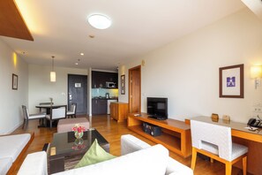 Een moderne woonkamer met een flatscreen televisie, een eethoek met een tafel en stoelen, en een keuken op de achtergrond.