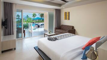 A hotel room with a bed, a sofa, a TV, and a balcony with a pool and umbrellas.