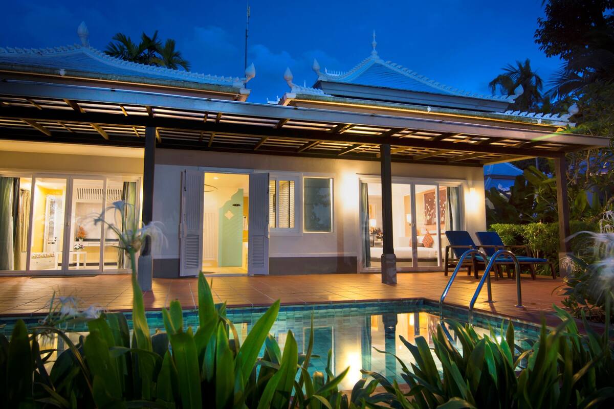 A modern hotel with a pool, covered patio, and traditional architecture.