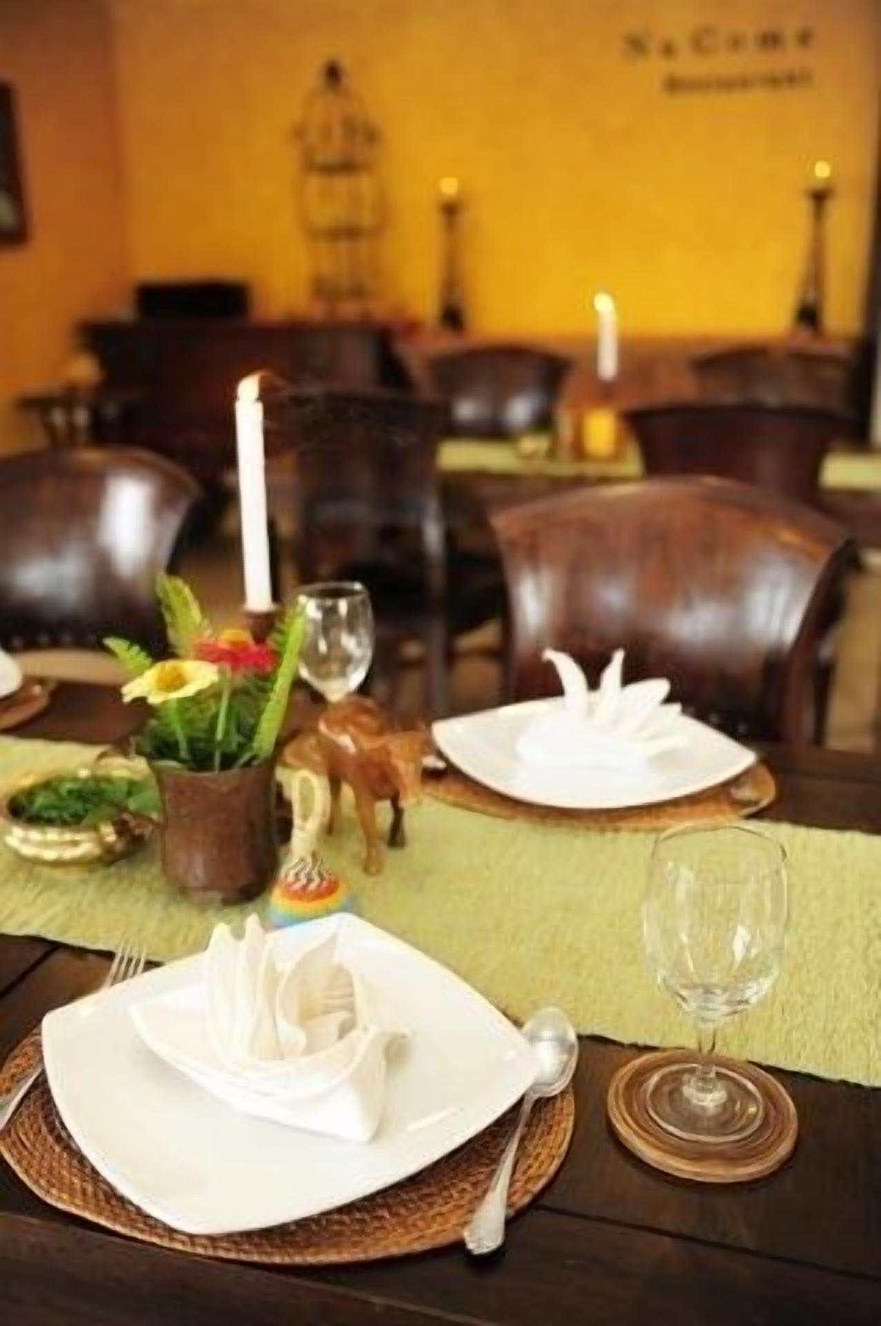 Una mesa de comedor dispuesta con platos, una vela, un vaso y un objeto decorativo pequeño.