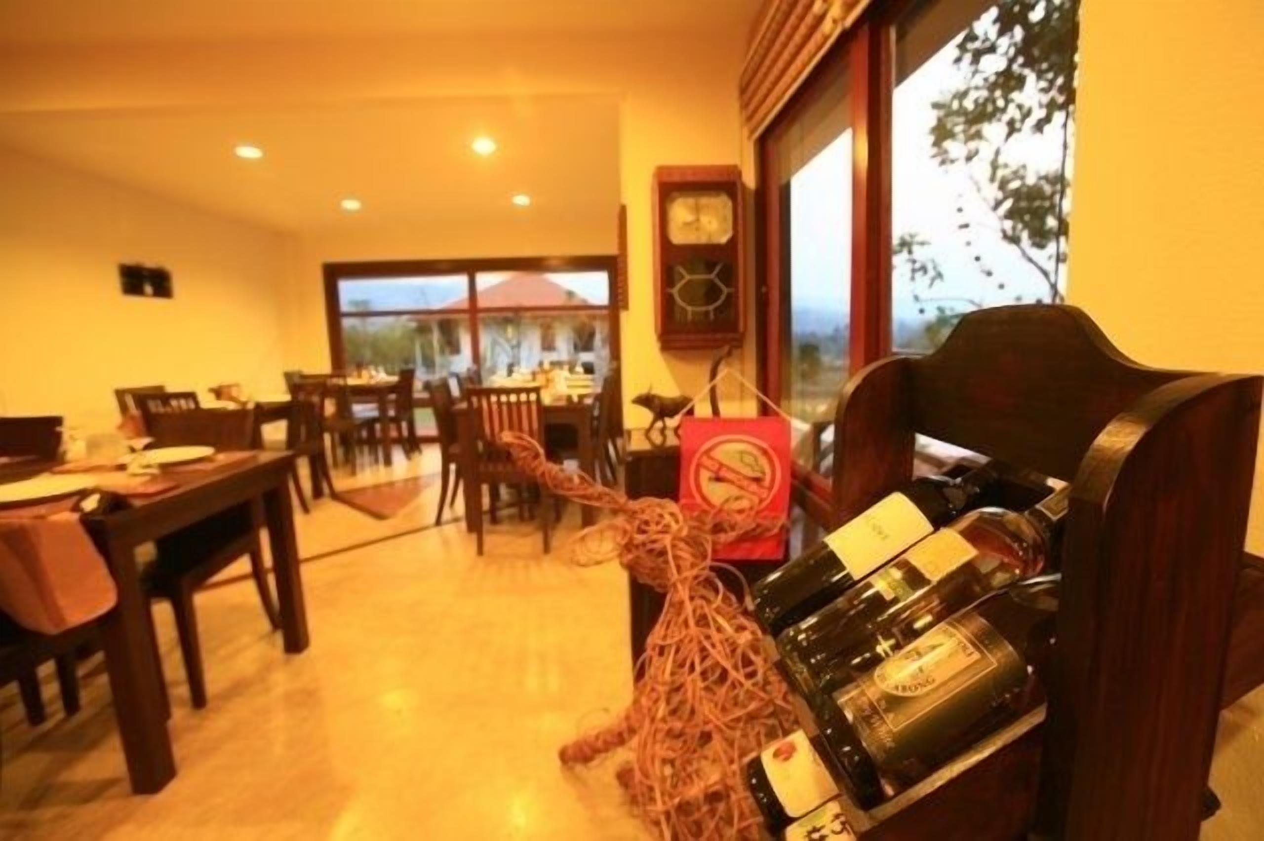 Un comedor con muebles de madera, un reloj en la pared y un porta botellas con botellas.