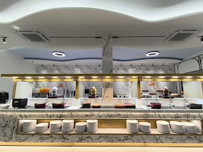Une cuisine moderne avec des plans de travail en marbre, un îlot central doté d’un évier et un éclairage suspendu au plafond.