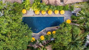 An aerial view of a swimming pool surrounded by palm trees and yellow umbrellas, with lounge chairs and a paved walkway. - Nai Yang Beach Resort & Spa (Sa Khu)