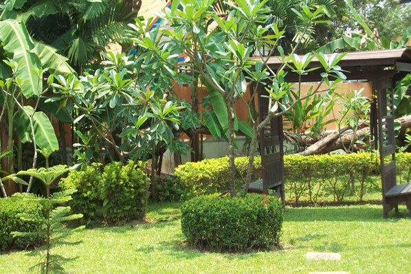 A lush garden with various green plants and a wooden pergola structure. - Lawana Resort (Koh Samui)
