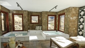 A spa room with two hot tubs, a seating area, and a towel rack. - Los Cerros del Chalten Boutique Hotel (El Chalten)