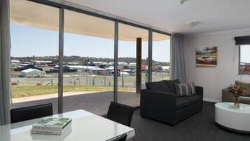 Habitación de hotel moderna con un amplio ventanal que ofrece vistas a coches estacionados y un paisaje distante.