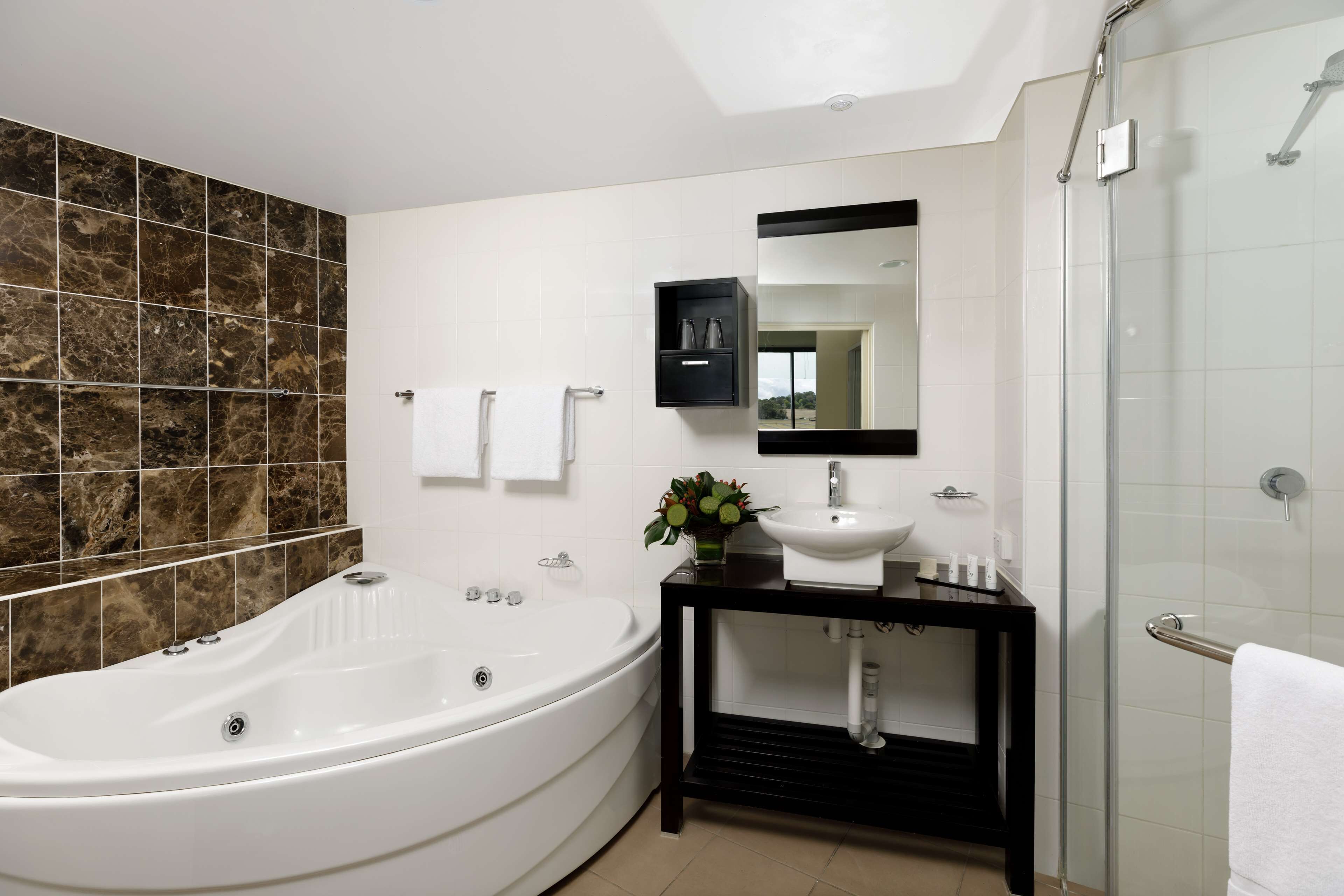 A modern bathroom with a freestanding bathtub, a vanity with a mirror, and a glass-enclosed shower.