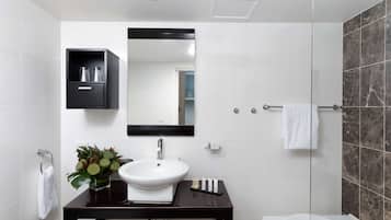 A modern bathroom with a white sink, dark vanity, and a glass shower enclosure.