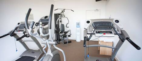 A gym with treadmills, elliptical machines, and a water dispenser.