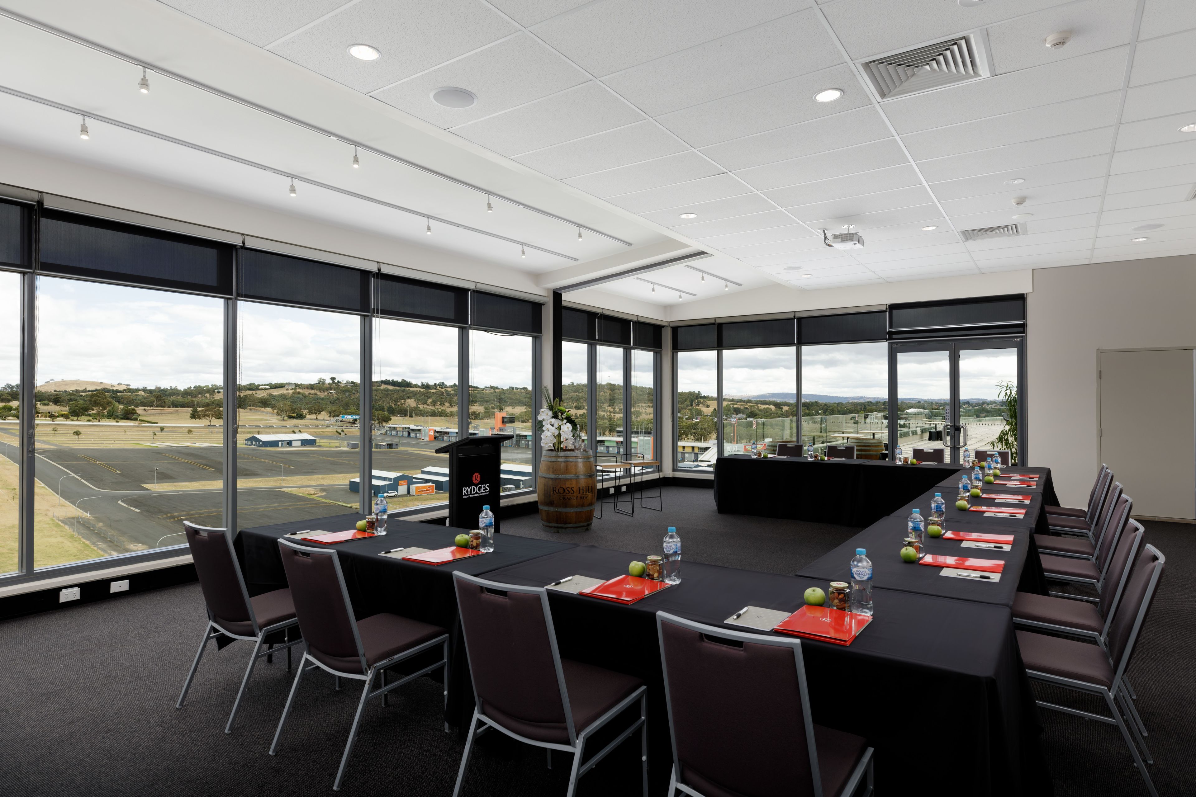 A conference room with a long table, chairs, and a view of an airport.