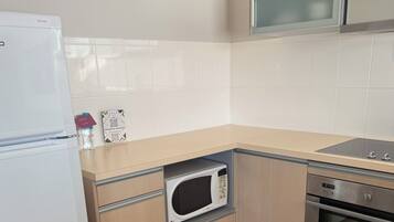 A compact kitchen with a microwave, oven, and a refrigerator.