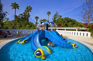 Una piscina al aire libre, sombrillas, sillones reclinables de piscina