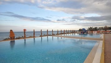 Una piscina al aire libre, sombrillas, sillones reclinables de piscina