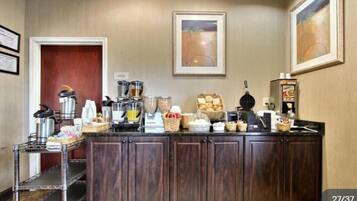 A kitchenette with a coffee maker, tea maker, and various food items on the counter.