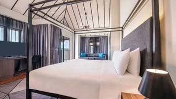 A modern hotel room with a four-poster bed, a desk, and a sofa in the background.