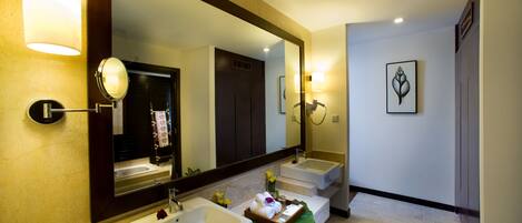 A bathroom with two sinks, a large mirror, and a green bath mat.