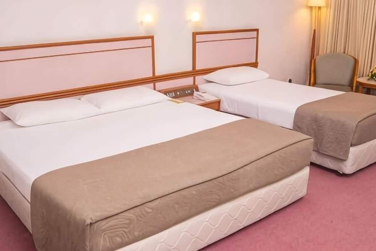 Ein Hotelzimmer mit zwei Betten, einem Nachttisch, einer Lampe und einem Sessel.