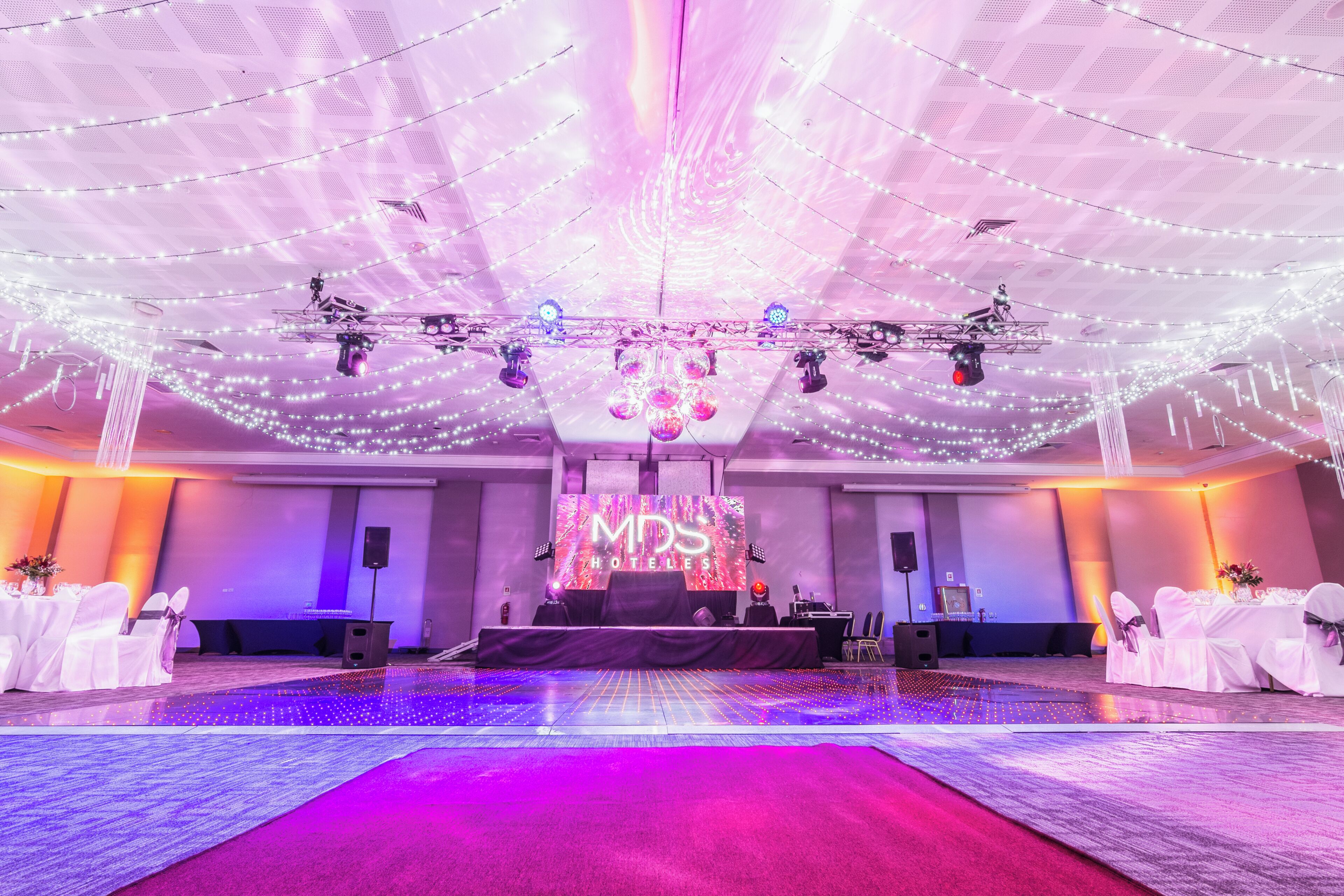 A hotel event space with a stage, lighting equipment, and a large LED screen displaying 'MD5 Hotels'.