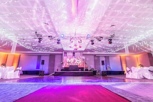Un espacio para eventos de hotel con escenario, equipo de iluminación y una gran pantalla LED que muestra 'MD5 Hotels'.
