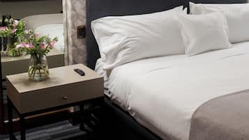 Una habitación de hotel con cama, mesita de noche y espejo.