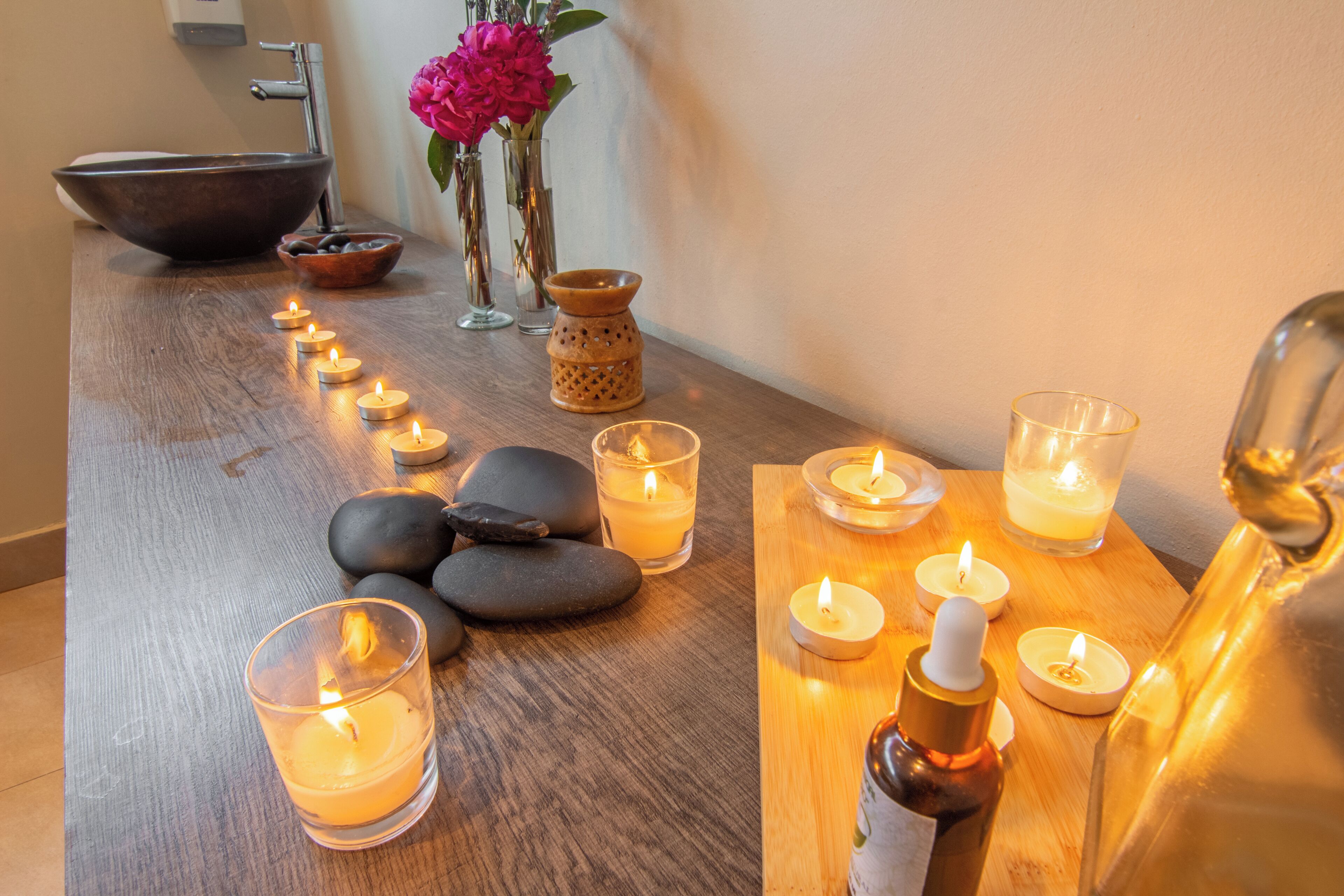 Una mesa de madera con velas, un bol y un florero con flores.