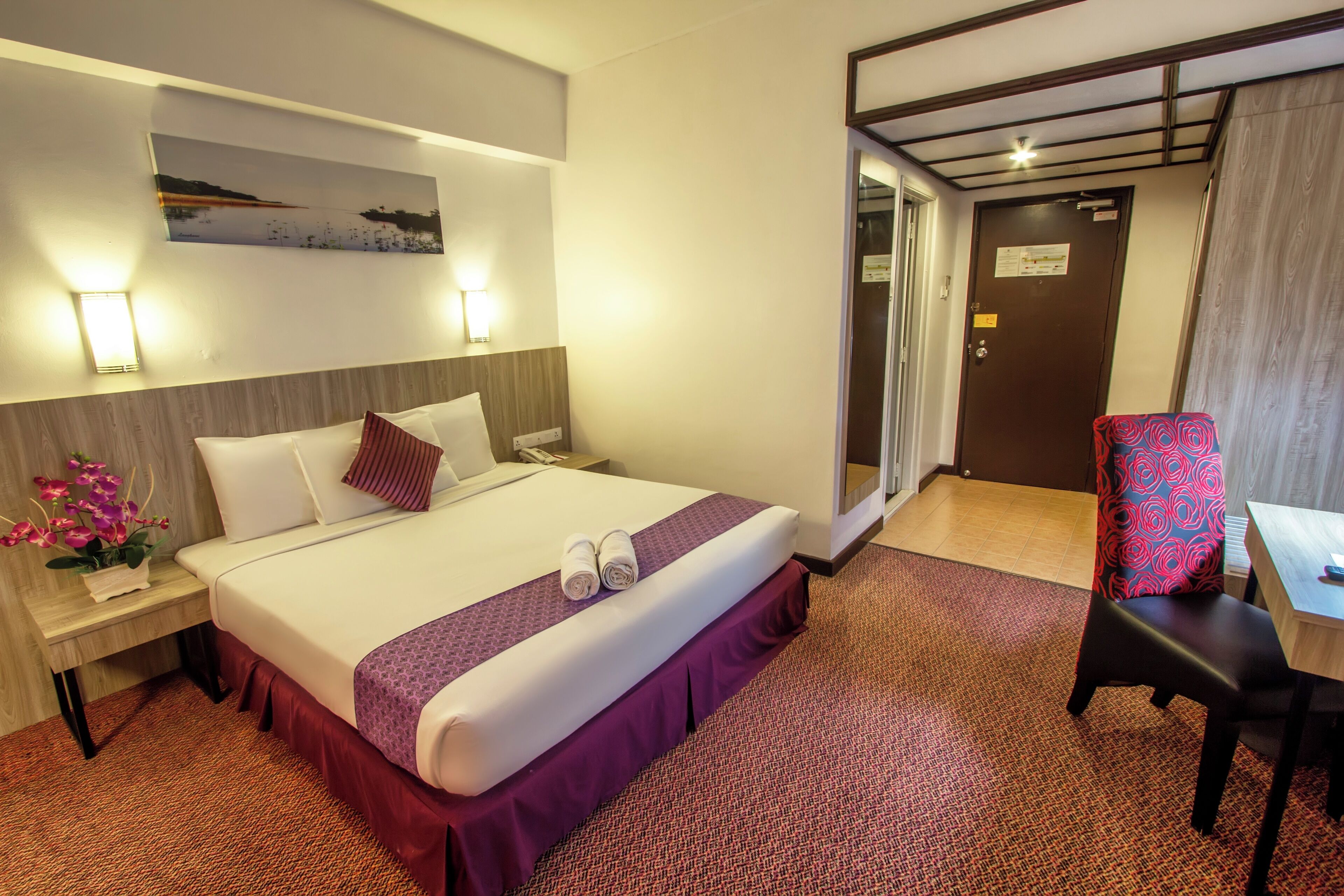 Ein Hotelzimmer mit Bett, Nachttisch, Lampe und einem Sessel.