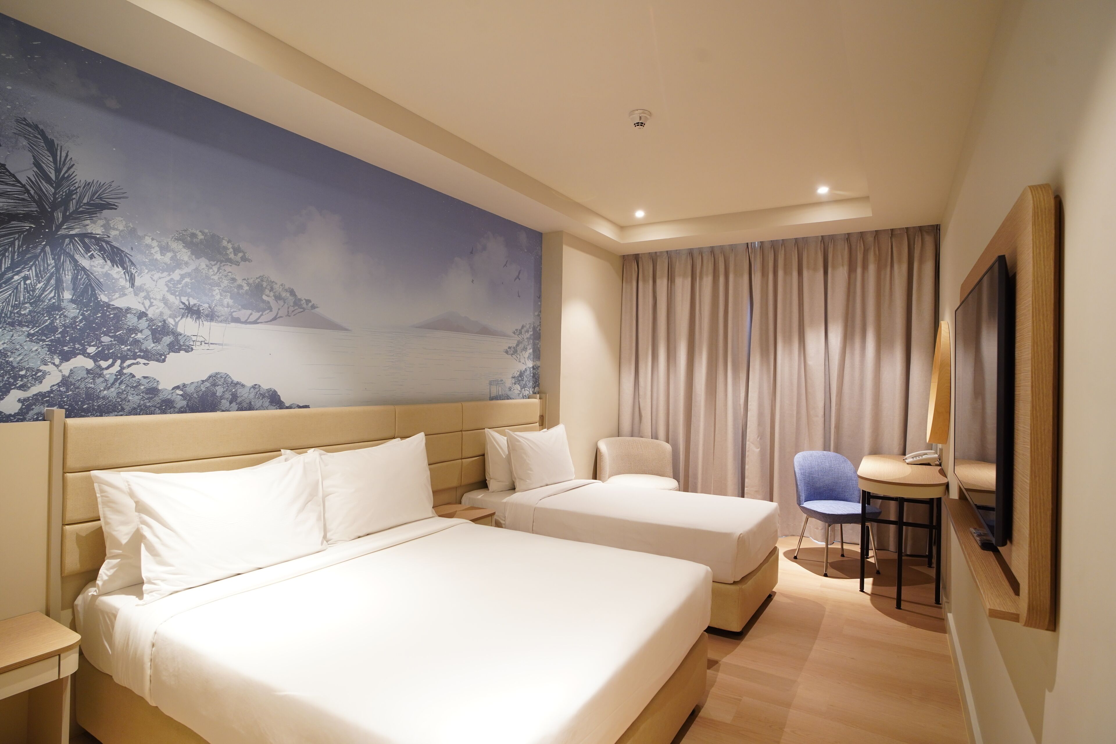 A hotel room with two beds, a desk, a chair, a large painting, and a mirror.
