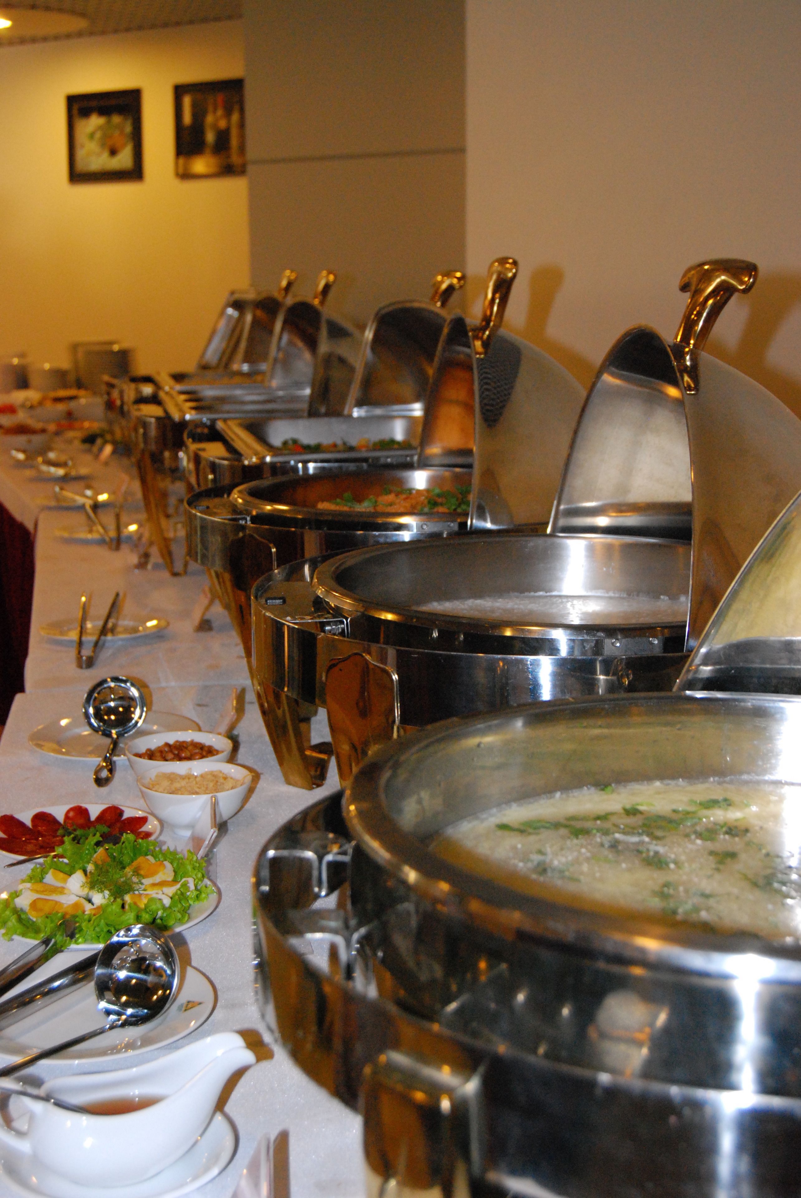 A buffet table with multiple serving dishes and utensils.