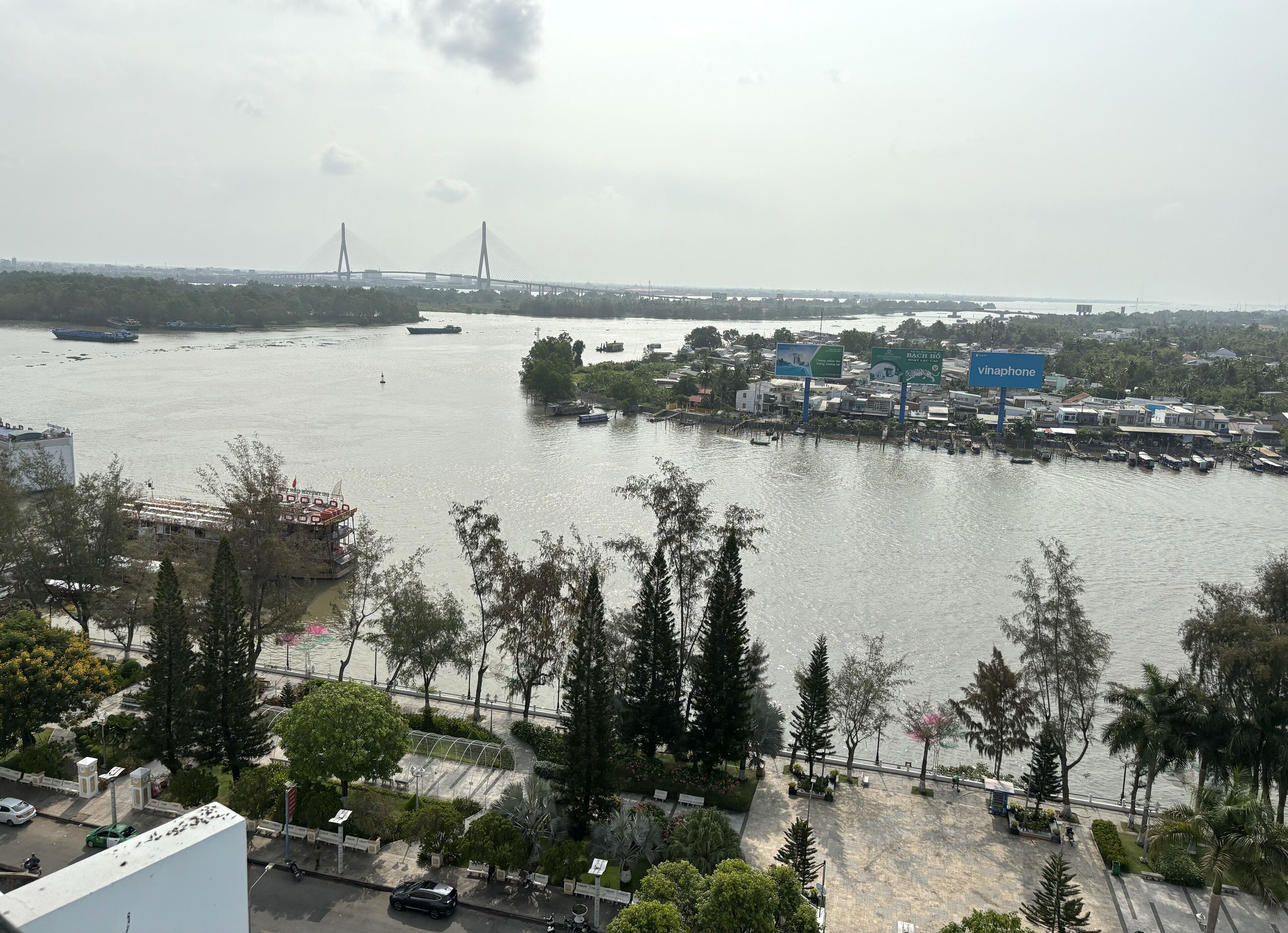 A riverside view with a bridge, boats, and a cityscape.