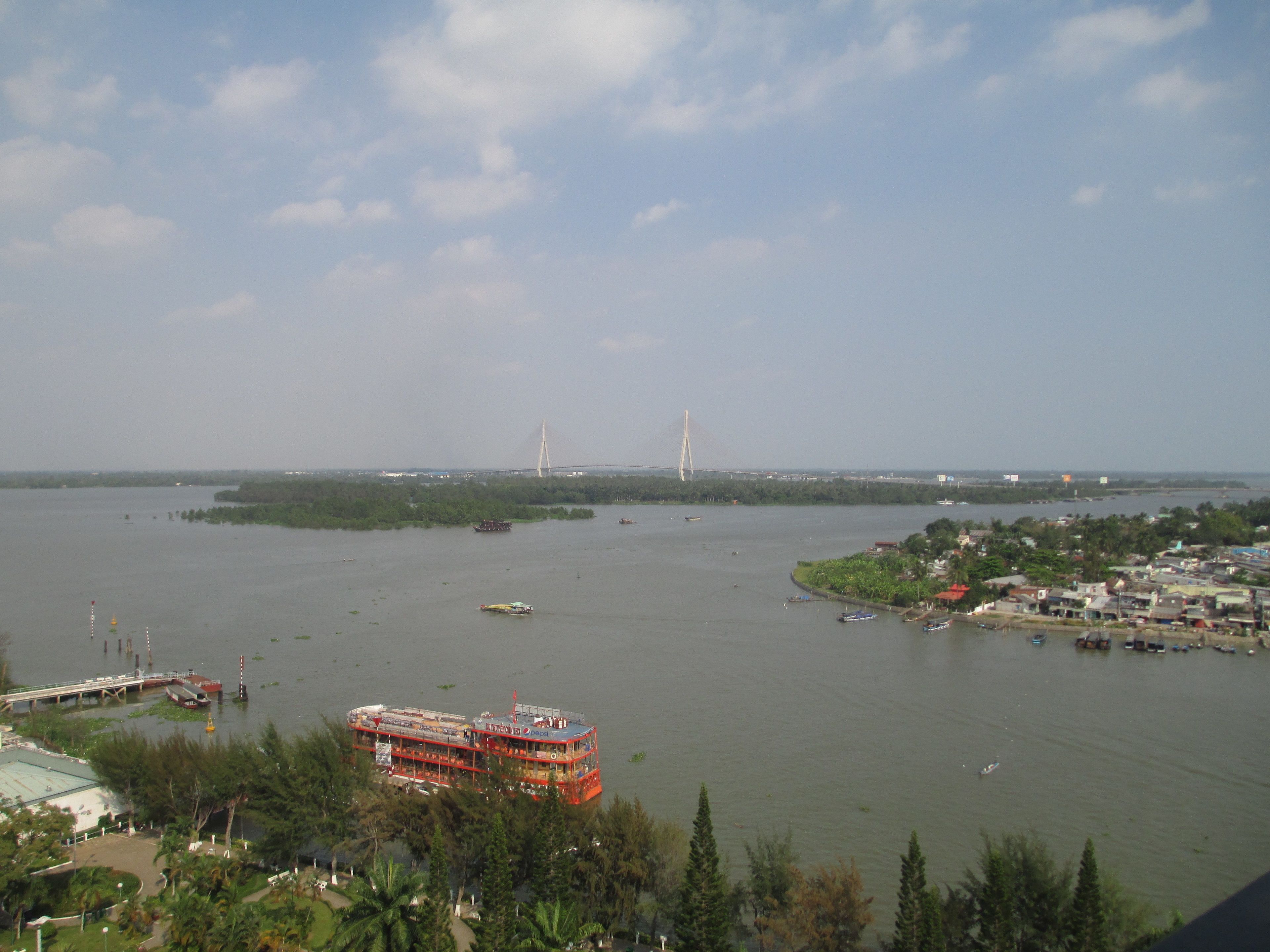 A river with a bridge and a red boat docked near the shore.