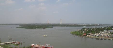 A river with a bridge and a red boat docked near the shore.