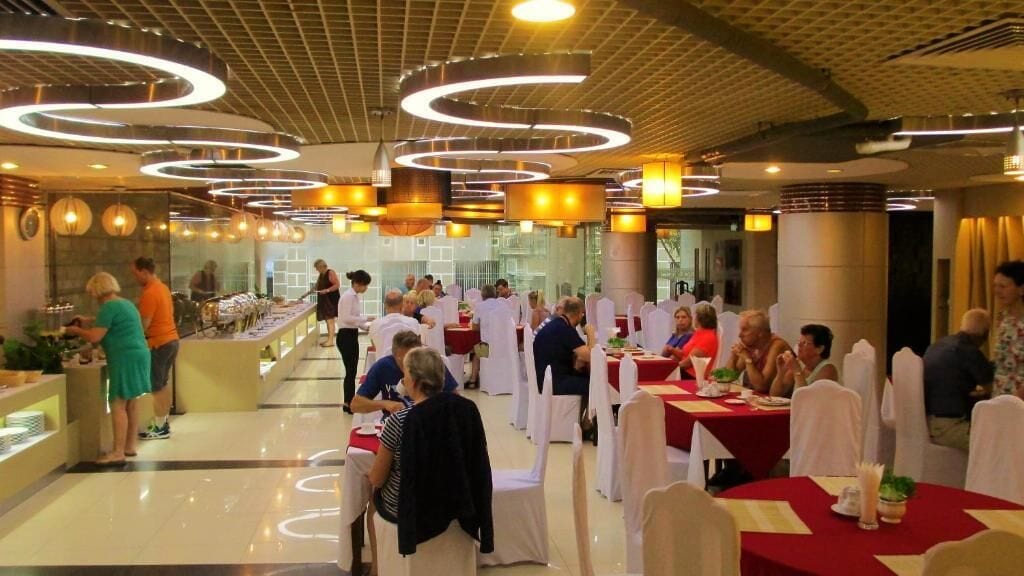 Un comedor con mesas redondas, manteles blancos y un diseño de techo moderno.