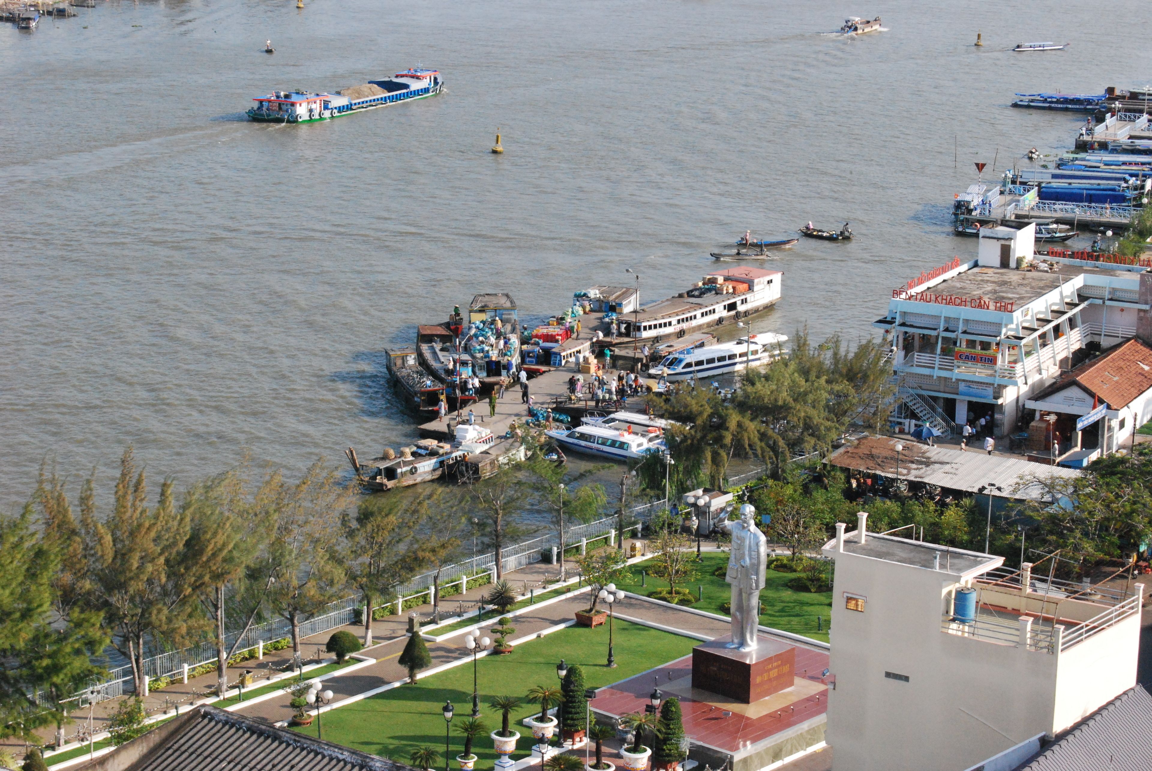 Une zone riveraine avec des bateaux, une statue et des bâtiments le long de la berge.