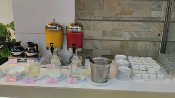 Ein reichhaltiges Buffet mit verschiedenen Speisen und Getränken, darunter Kaffee-, Tee- und Milchspender.