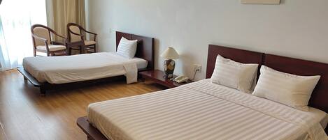 A hotel room with two beds, a chair, a nightstand, and a lamp.