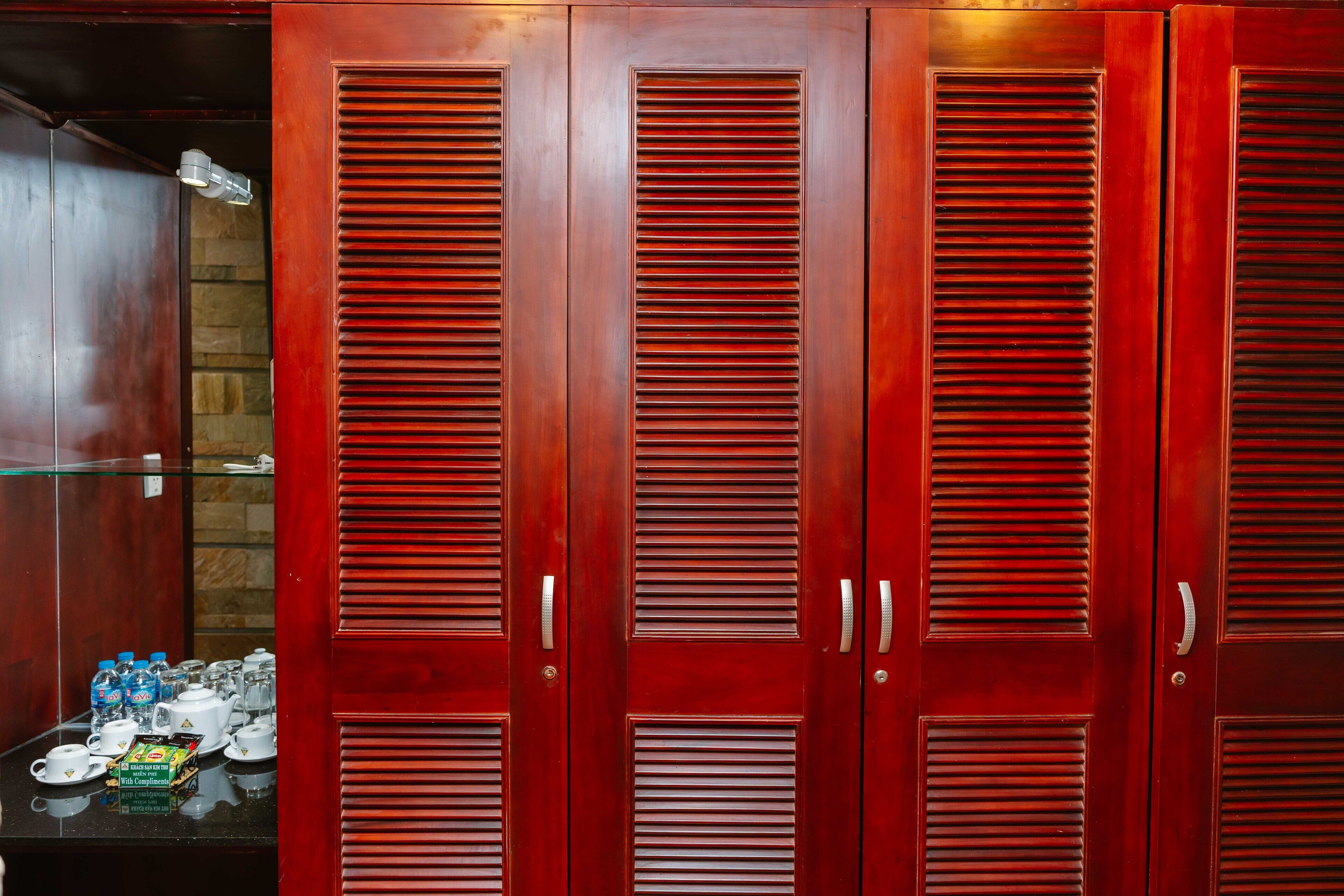 A set of wooden wardrobe doors with louvered panels and silver handles.